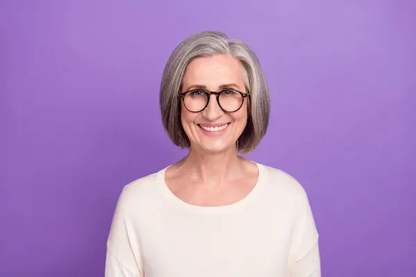 迷人的退休女工戴着眼镜笑着看着相机孤立的紫色背景的照片 — 图库照片