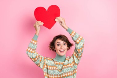 Photo of charming looking sweet nice girl young age holding red paper romantic heart symbol partners gift isolated on pink color background. clipart