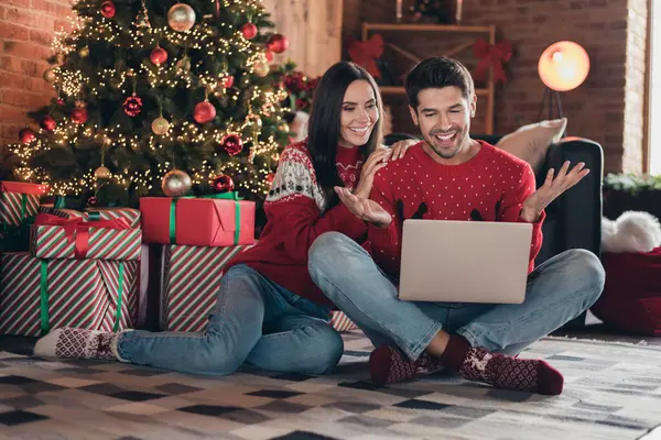 Full body cadre postcard of cheerful couple speaking with family members online using internet laptop to congratulate xmas holiday indoors.