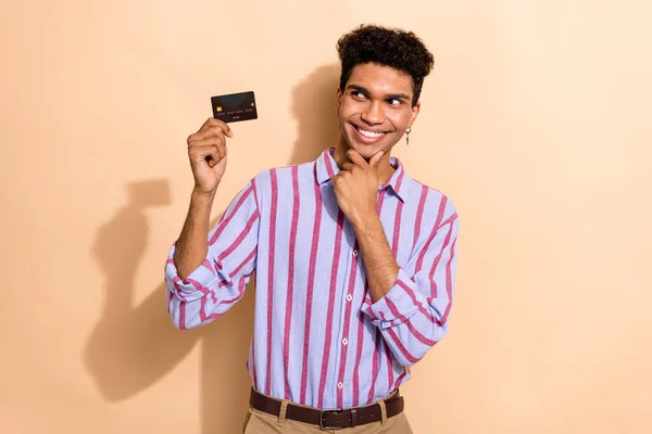 Photo of nice guy touch chin point empty space credit card dressed stylish striped formalwear garment isolated on beige color background.