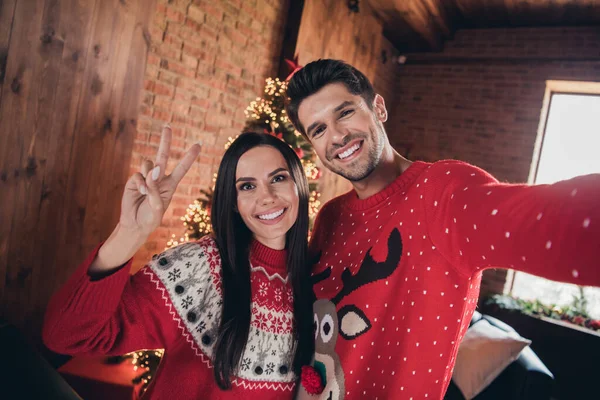 Selfie of young couple show v sign recording video greetings parents while celebrate jolly christmas isolated on illumination background.