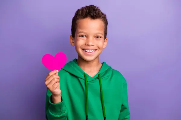 ファンキーな魅力的な小さな男の子の写真は ピンクの紙の心臓を上昇させる緑のパーカーをドレスアップしました 紫色の背景 — ストック写真
