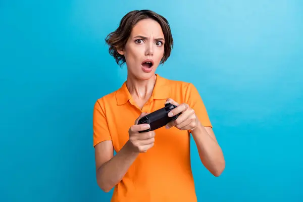 Photo of impressed upset lady wear orange t-shirt loosing playstation game isolated blue color background.
