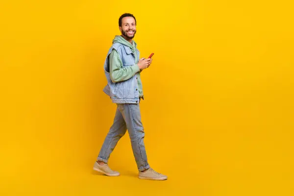 stock image Full body size cadre of satisfied blogger guy with smartphone walking eshopping advertisement sale isolated on yellow color background.