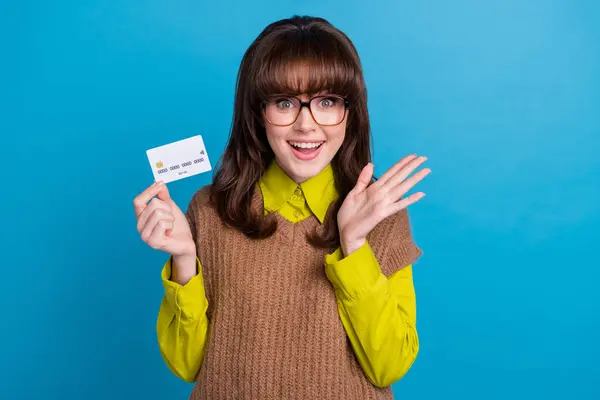 Photo of excited funky lady wear brown vest spectacles holding credit card isolated blue color background.