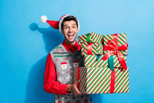 照片上漂亮的年轻男性拿着兴奋的商业大堆礼物 穿着圣诞礼物 头戴印有蓝色背景图案的帽衫 — 图库照片