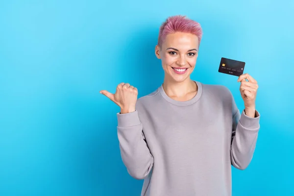 Stock image Photo of optimistic nice woman dressed gray sweatshirt indicating offer empty space hold plastic card isolated on blue color background.