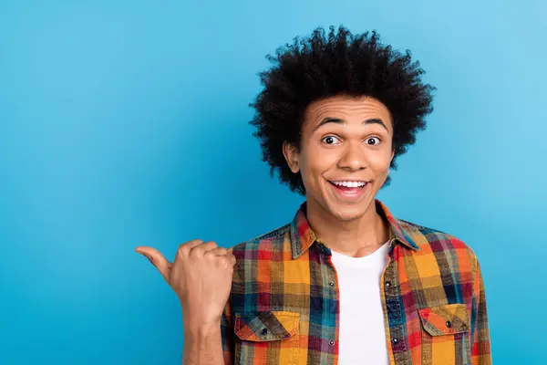 Stock image Photo of cool excited guy dressed checkered shirt showing thumb empty space isolated blue color background.