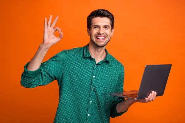 Photo of funky cool guy wear green shirt showing okey working modern gadget isolated orange color background.