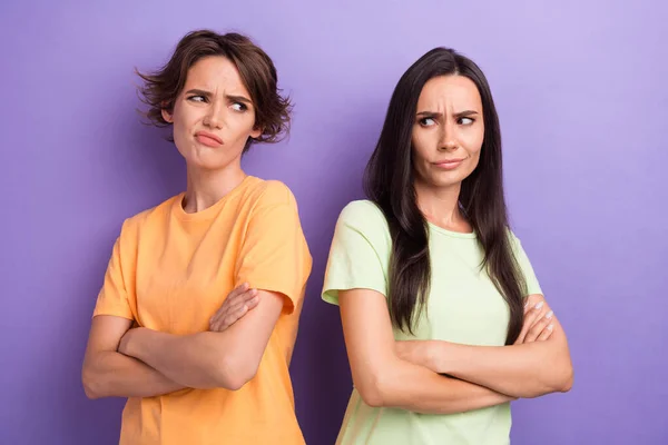 Photo of unhappy upset ladies wear t-shirts arms folded having quarrel isolated violet color background.