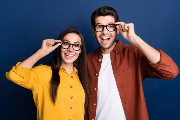 Portrait of two astonished corporate workers hand touch eyewear open mouth unbelievable isolated on blue color background.