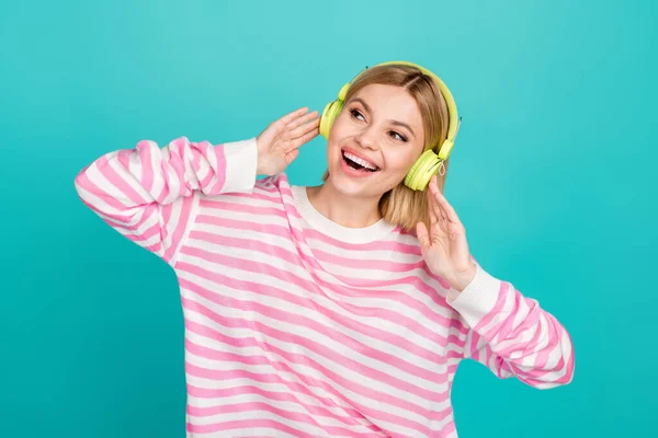 魅力的なミレニアル世代の少女ワイヤレスヘッドフォンの写真 ストライプピンクのセーターを着用して笑うことは シアンカラーの背景で幸せに見えます — ストック写真