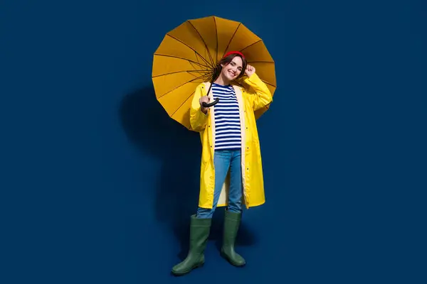 照片全貌漂亮的女友装模作样漫不经心抱着黄色阳伞雨天雨天与蓝色背景隔离 — 图库照片