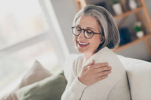 Фото Очаровательной Пожилой Женщины Белых Очках Кардигана Обнимающей Себя Закрытыми — стоковое фото
