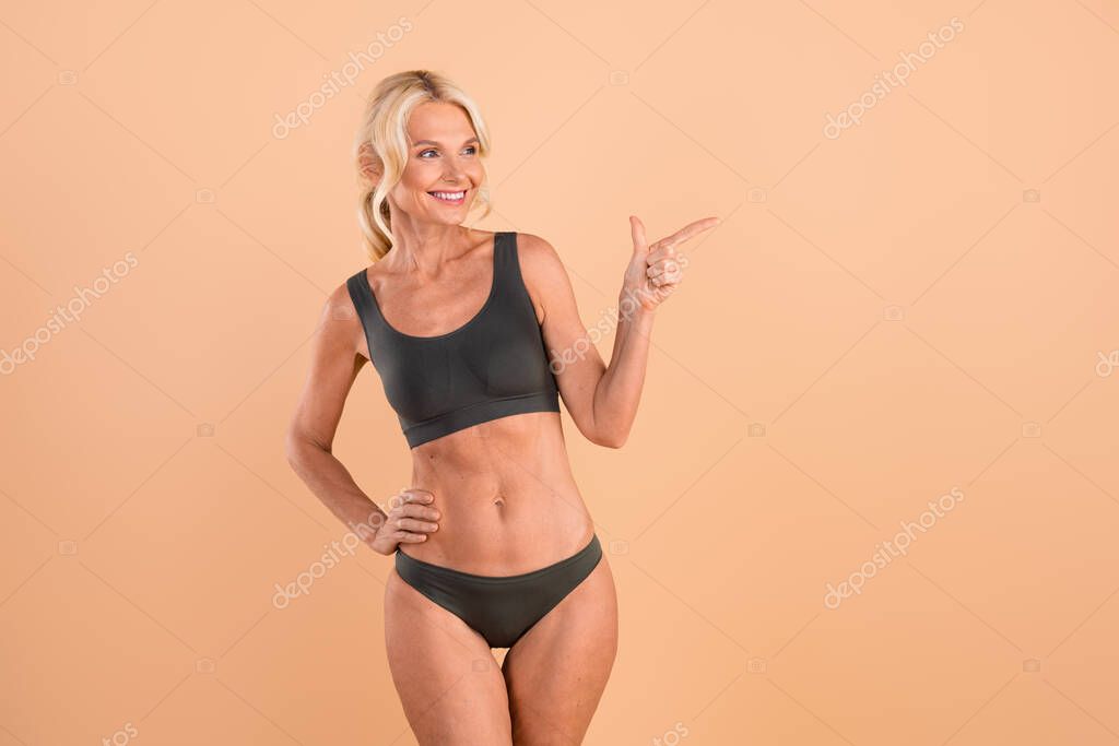 Photo of slender gray underclothes model pensioner woman directing finger mockup interested sunscreen ad isolated on beige color background.