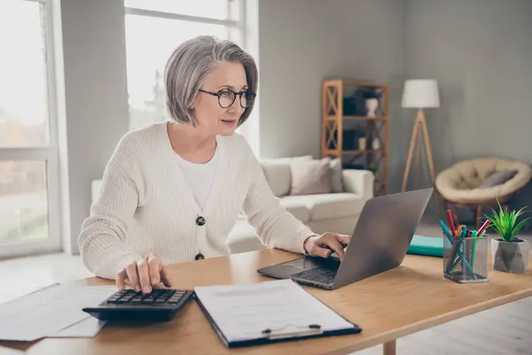 stock image Photo of serious confident senior lady accountant dressed white cardigan counting bills modern gadget indoors house room.