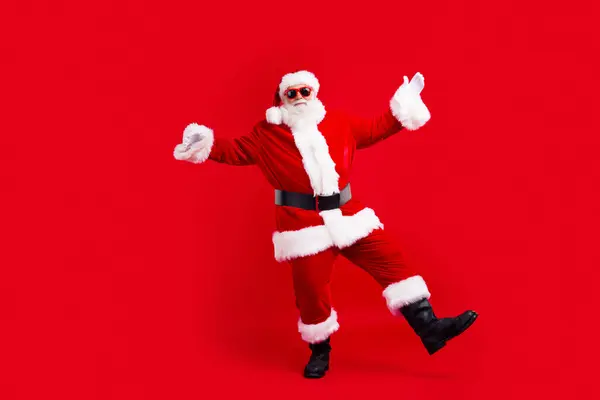 良い気分のおじいちゃんのフルサイズの写真は 赤い色の背景に隔離されたクリスマスのお祝いで踊るメガネでサンタの衣装を着ます — ストック写真