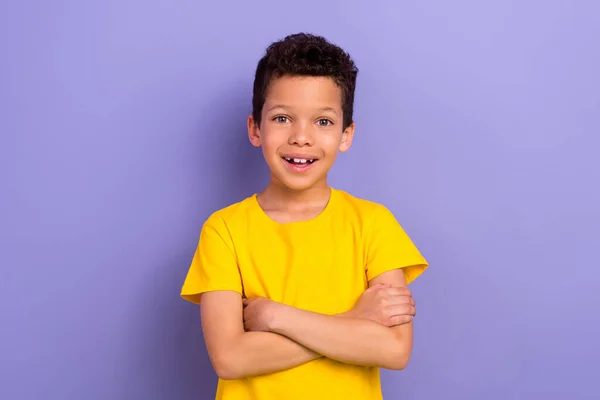 陽気な興奮した少年が黄色のトレンディな服を着る写真は紫色の背景に隔離された交差した腕と立っています — ストック写真