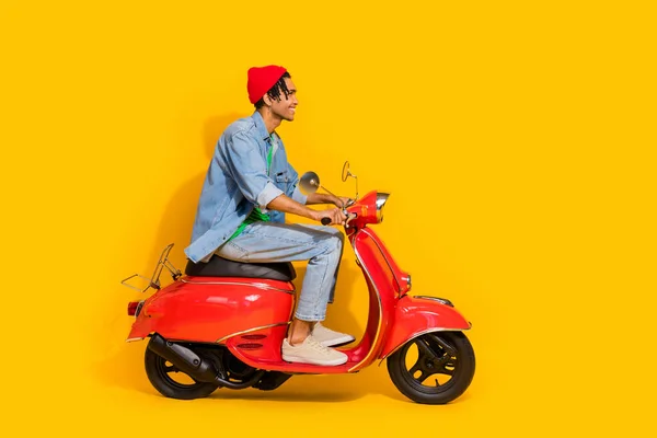 吸引人的年轻人驾驶复古红色摩托 穿着时尚牛仔裤 背景为黄色 — 图库照片