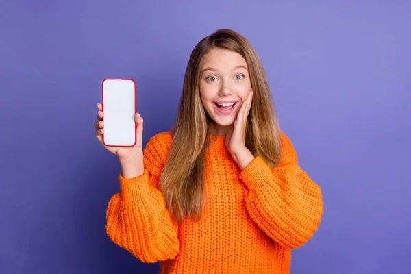 年轻女孩穿着橙色套头毛衣给你带来惊喜的照片 你可以用紫色背景隔离扫描Qr代码智能手机屏幕 — 图库照片