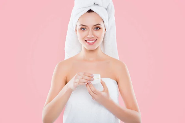 Portrait of pretty sexy woman in towel and turban on head holding presenting cream for problem combined face skin isolated on white background. Wellness wellbeing concept.