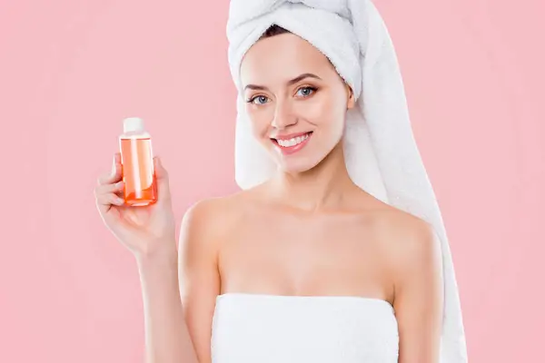 Portrait of pretty woman in towel and turban on head demonstrate lotion shower gel for dry body skin isolated on white background.