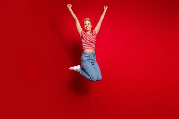 楽しんだ喜びの女の子の完全な長さの写真 スタイリッシュな服を着る ジャンプを祝う 成功の喜び 赤い色の背景で隔離された勝利 — ストック写真