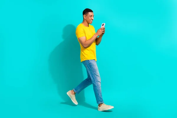正面正派年轻人行走的全景照片用智能手机博客隔离在青色背景下 — 图库照片