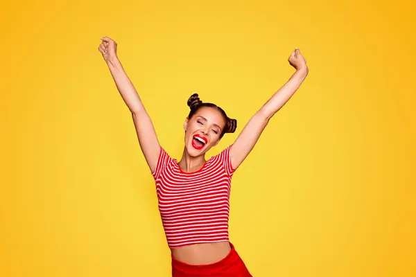 Happy celebrating winning success woman isolated on red baskground with arms raised up above her head. Success and life goals concept.