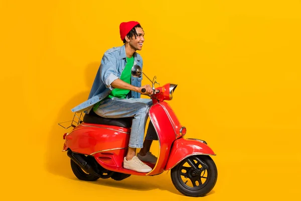可爱的年轻男子骑摩托车穿着时尚牛仔裤衣服 背景为黄色 全长照片 — 图库照片