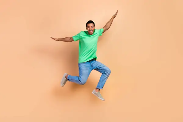 无忧无虑的快乐男人穿着时髦的T恤牛仔裤 手持手掌 像被米色背景隔离的翅膀 — 图库照片