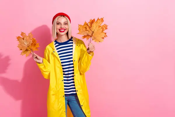 かわいい陽気な女性の写真は オレンジ色の葉を保持するレインコートを着用します 空のスペース ピンク色の背景 — ストック写真
