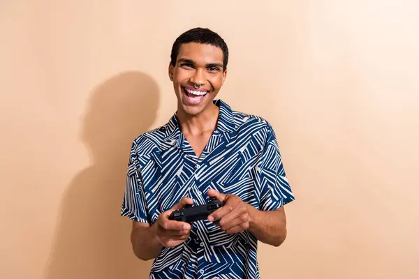 Photo of cheerful good mood guy wear print shirt enjoying playstation game isolated beige color background.