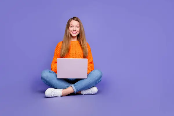紫色の背景で隔離された試験の準備のために遠くの研究のためにラップトップを使用して陽気な十代の少女の全身の長さの写真 — ストック写真