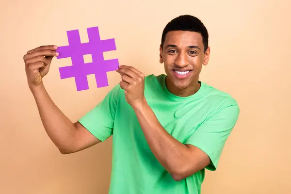 Photo portrait of nice young guy hold hashtag social media wear trendy green garment isolated on beige color background.