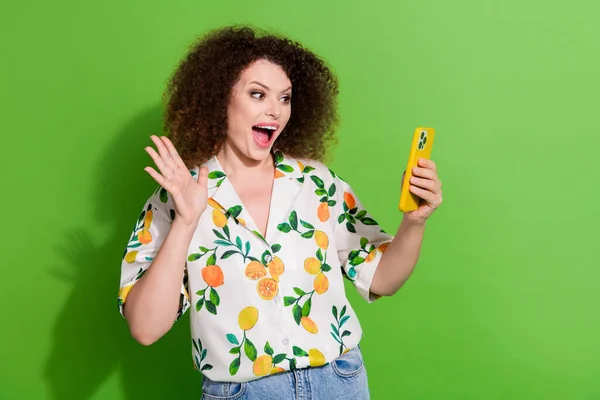 Photo of excited funky lady wear print shirt recording video vlog modern device waving arm hi isolated green color background.