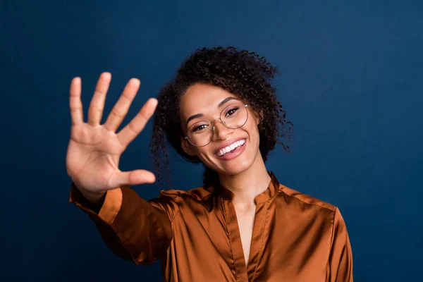 Photo of friendly excited lady wear silk brown shirt spectacles waving arm palm hello isolated blue color background.