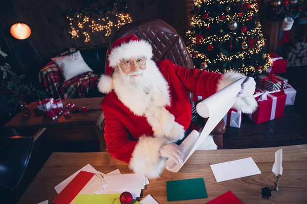 照片上的心情很好 圣诞老人穿着红色服装 准备新年礼物清单在家里北极 — 图库照片