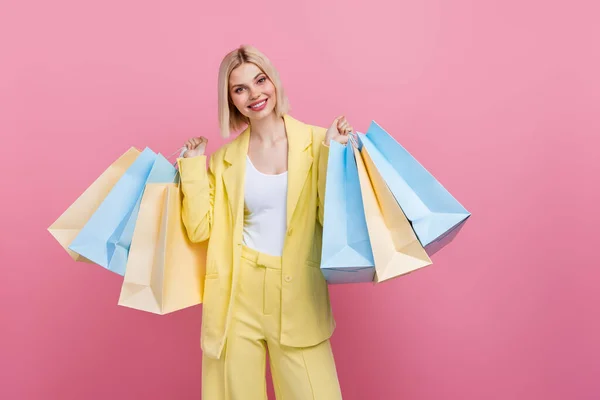开朗雅致的人物形象手握商场购物袋空旷的空间广告与粉色背景隔离 — 图库照片