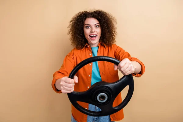 Photo of cheerful lovely girl wear trendy orange clothes hands hold steering wheel test drive lesson isolated on beige color background.
