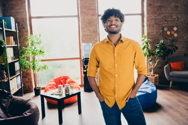 Photo portrait of attractive young man wear yellow shirt hands pockets confident administrator modern workplace room home design.
