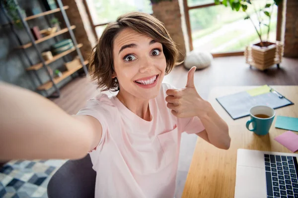 Selfie shooting young businesswoman bob hair thumb up recommendation her first job intern working remote from coworking zone background.