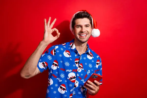 Портрет Удовлетворенного Оптимистичного Человека Одет Санта Шляпу Держать Смартфон Показывая — стоковое фото