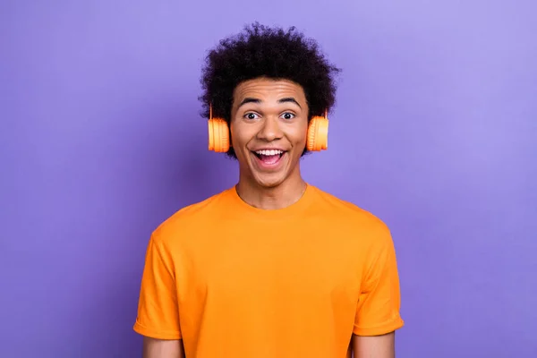 疯狂的男人穿着橙色T恤时髦的衣服笑着听着最喜欢的专辑耳机被紫色背景隔开的照片 — 图库照片