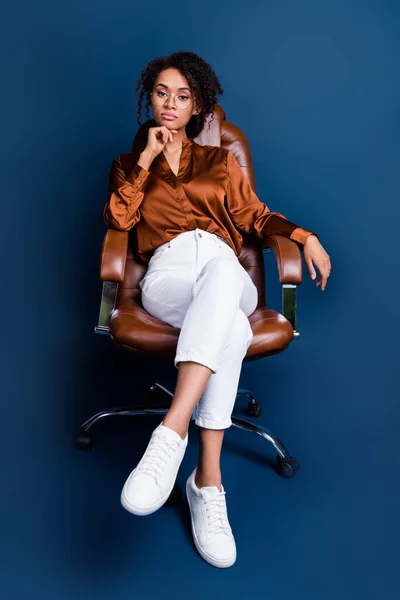 Vertical photo of pretty young girl strict boss armchair deal dressed stylish brown silk formalwear isolated on dark blue color background.