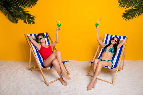两个女孩在避暑胜地休息的照片举杯敬酒 让我们在鲜活的色彩背景下完美地放松一下 — 图库照片