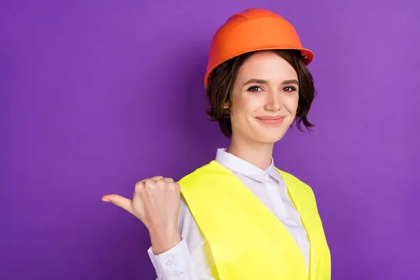 Profile photo of optimistic nice brunette hair lady point empty space wear builder uniform isolated on purple color background.