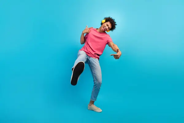 ハンサムな若い男性ダンサーイエローイヤーイヤホンのフルボディ写真は ブルーカラーの背景に隔離されたスタイリッシュなピンクの服を興奮させます — ストック写真