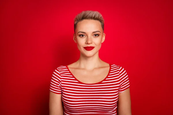 ストライプスタイリッシュなTシャツを身に着けている女性の白いショートヘアカットの肖像画は 赤い色の背景で隔離された明るいポザードで自信を持って見えます — ストック写真