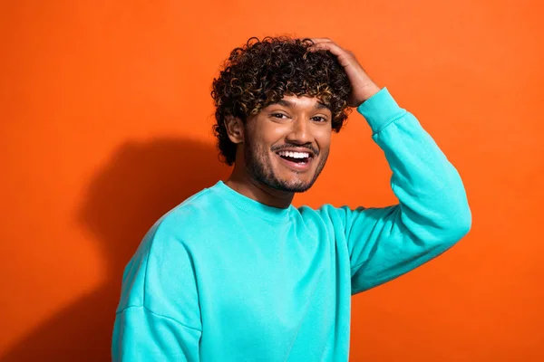 Portrait of positive friendly person beaming smile arm touch wavy hairdo isolated on orange color background.